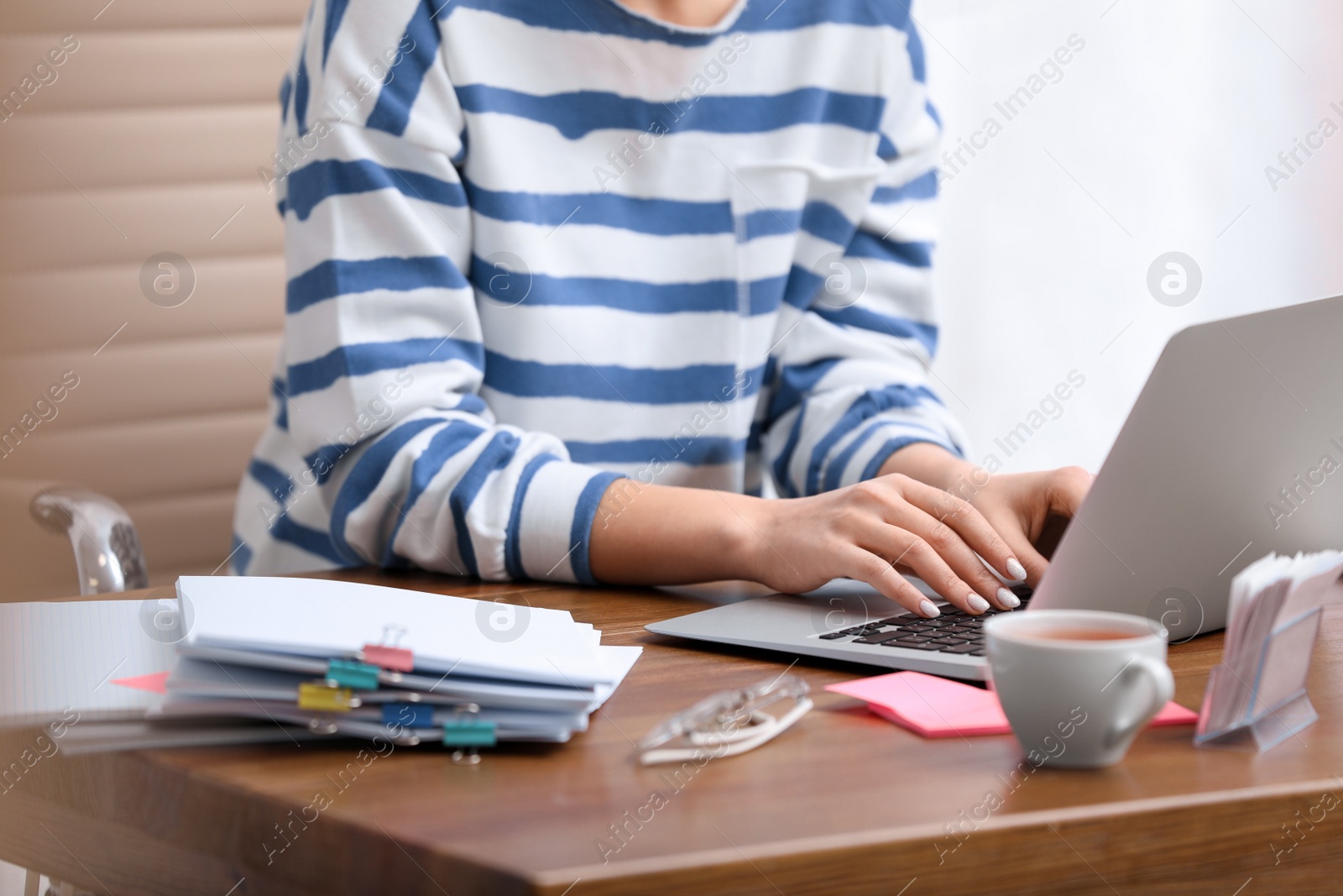 Photo of Young journalist working with laptop in office, closeup