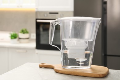 Photo of Water filter jug on light table in kitchen, closeup. Space for text