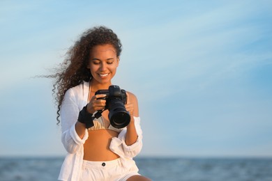 African American photographer with professional camera near sea