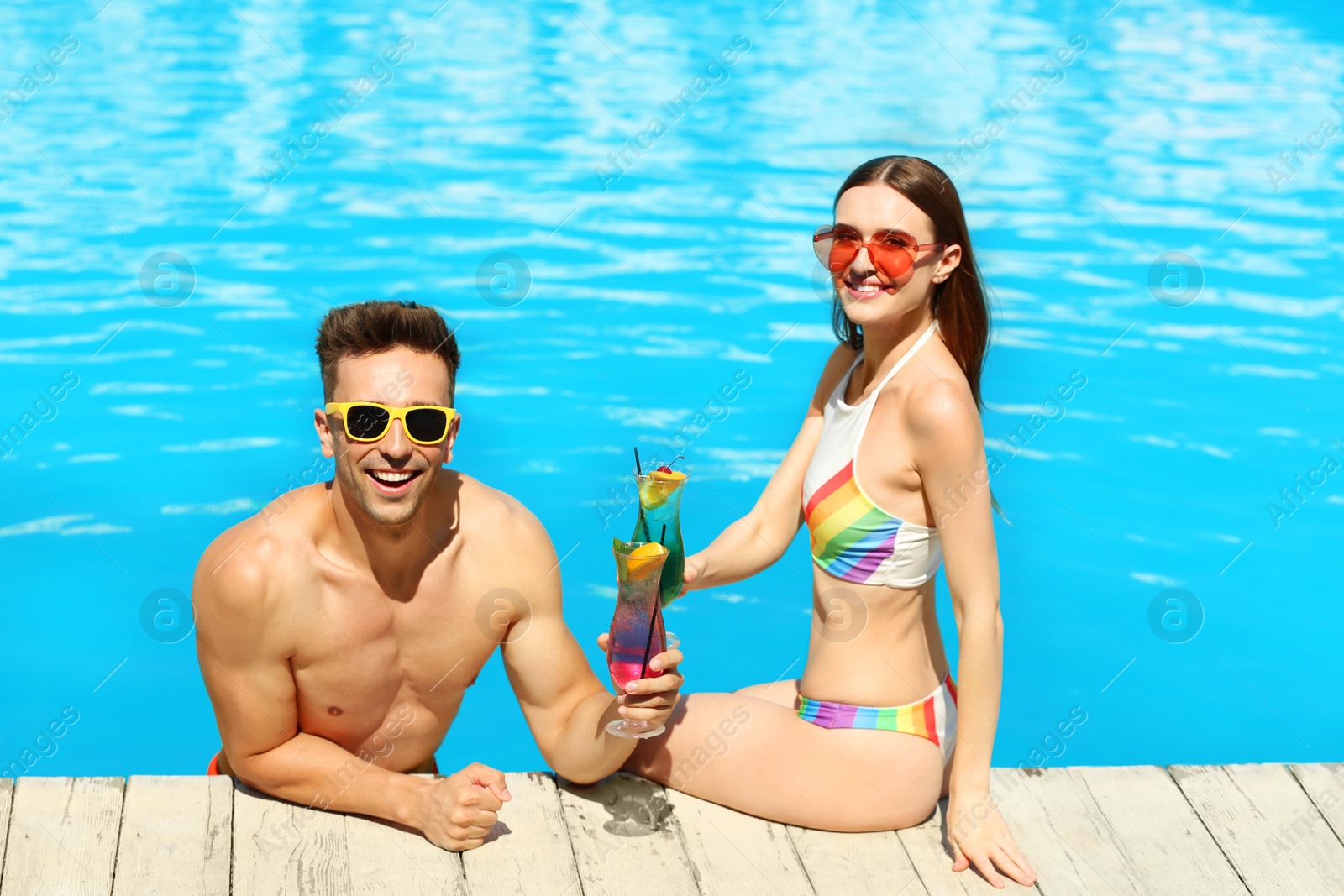 Photo of Happy young couple with cocktails resting at swimming pool