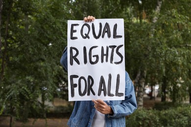 Woman holding sign with text Equal rights for all outdoors