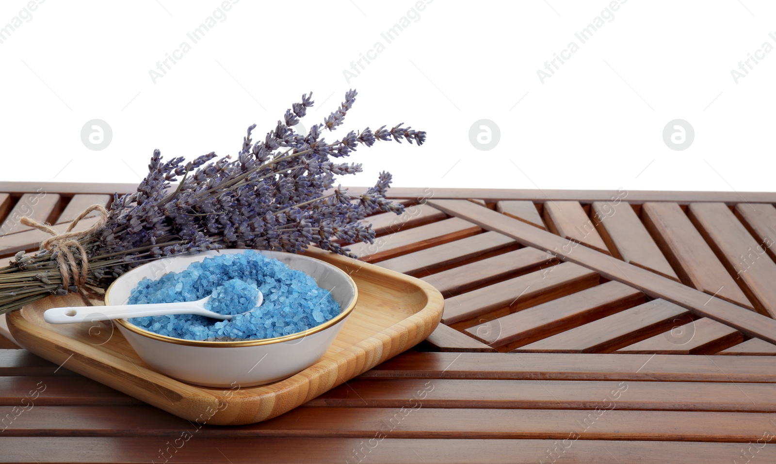 Photo of Bowl with blue sea salt and lavender flowers on wooden table against white background