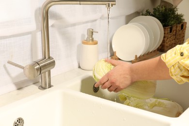 Photo of Woman washing fresh chinese cabbage under tap water in kitchen sink, closeup