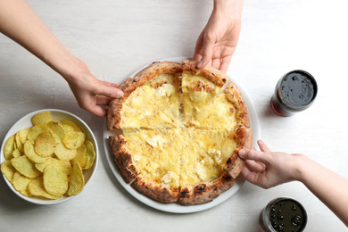 People taking tasty cheese pizza at white wooden table, top view