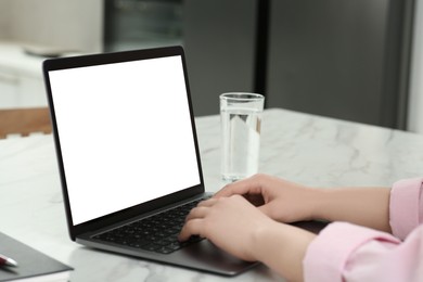 Photo of Woman using laptop at white table indoors, closeup