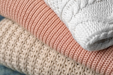 Photo of Stack of folded warm knitted sweaters, closeup