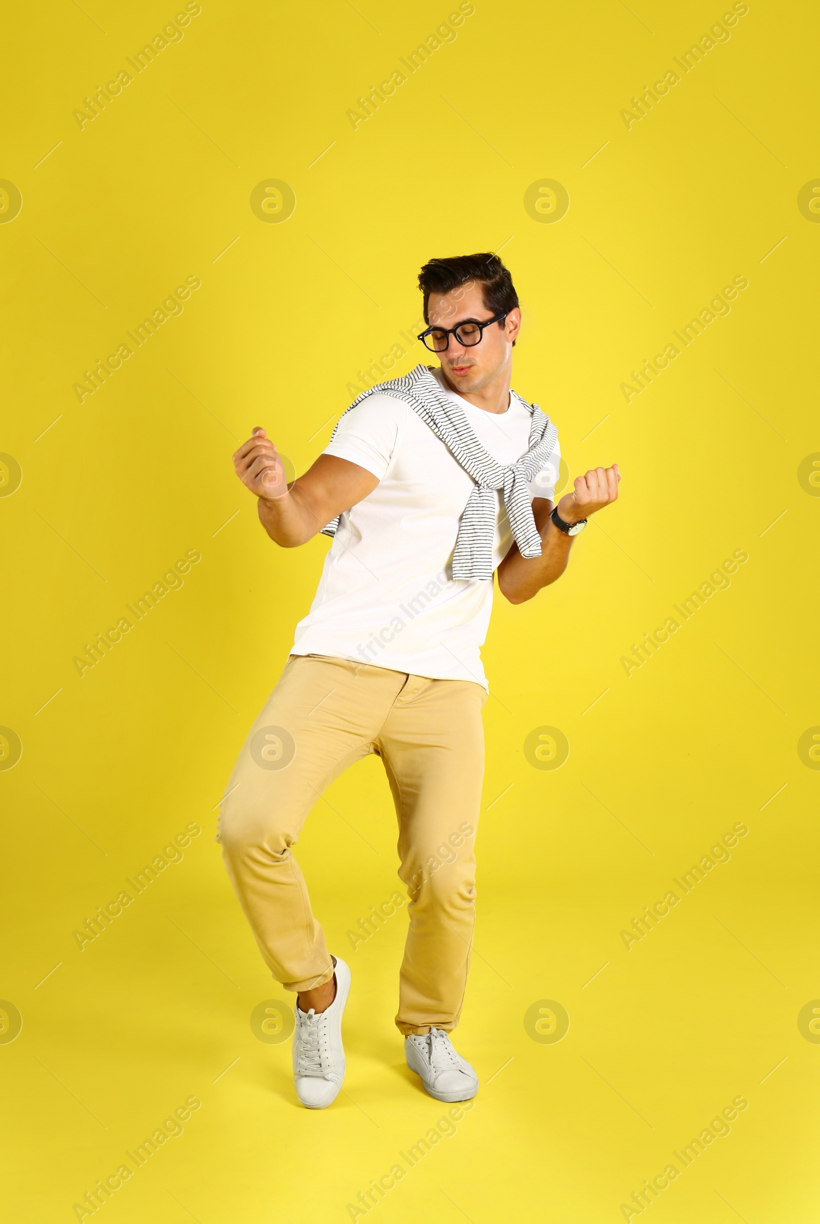 Photo of Handsome young man dancing on yellow background