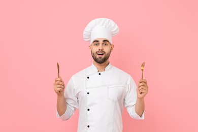 Professional chef holding kitchen utensils on pink background