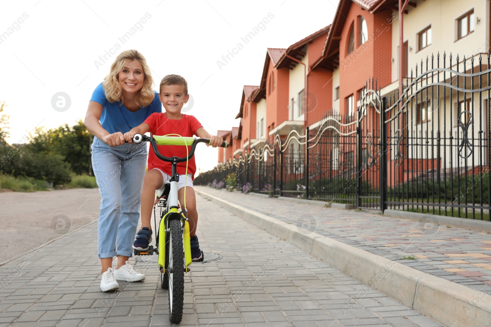 Photo of Happy mother teaching her son to ride bicycle in city