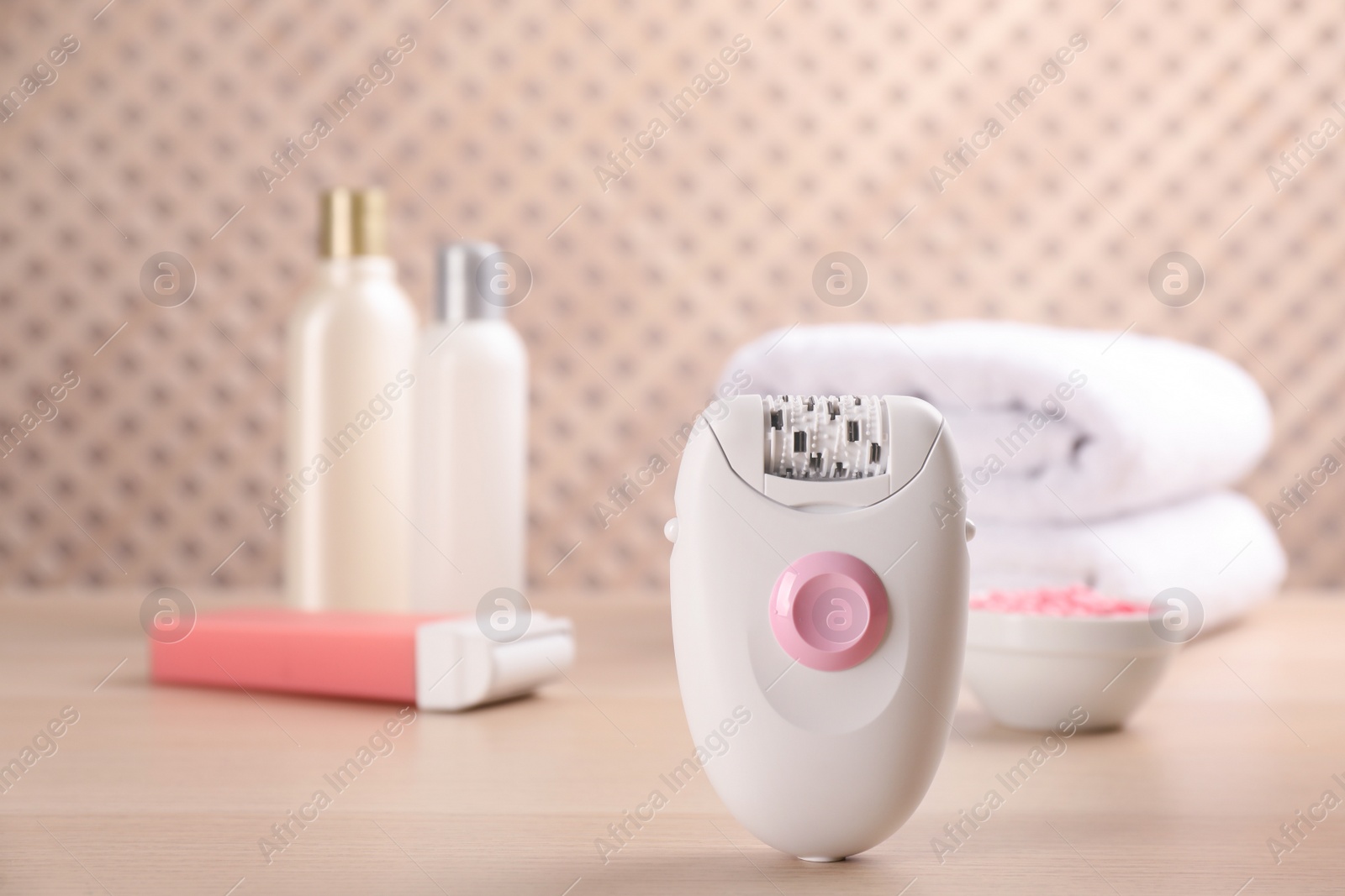 Photo of Modern epilator and other hair removal products on wooden table. Space for text