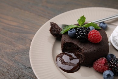 Photo of Delicious chocolate fondant served with fresh berries on wooden table, closeup. Space for text