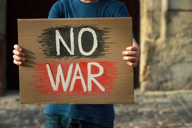 Photo of Man holding poster with words No War on city street, closeup