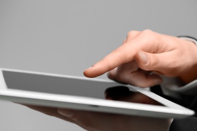 Closeup view of woman using modern tablet on grey background