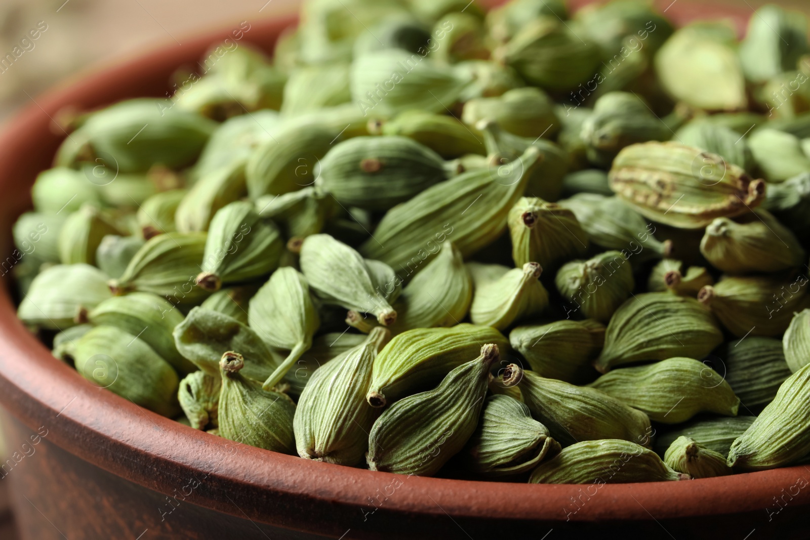 Photo of Bowl of dry green cardamom pods, closeup