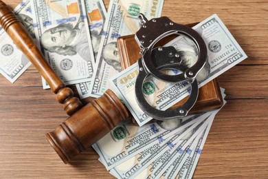 Photo of Judge's gavel, money and handcuffs on wooden table, flat lay