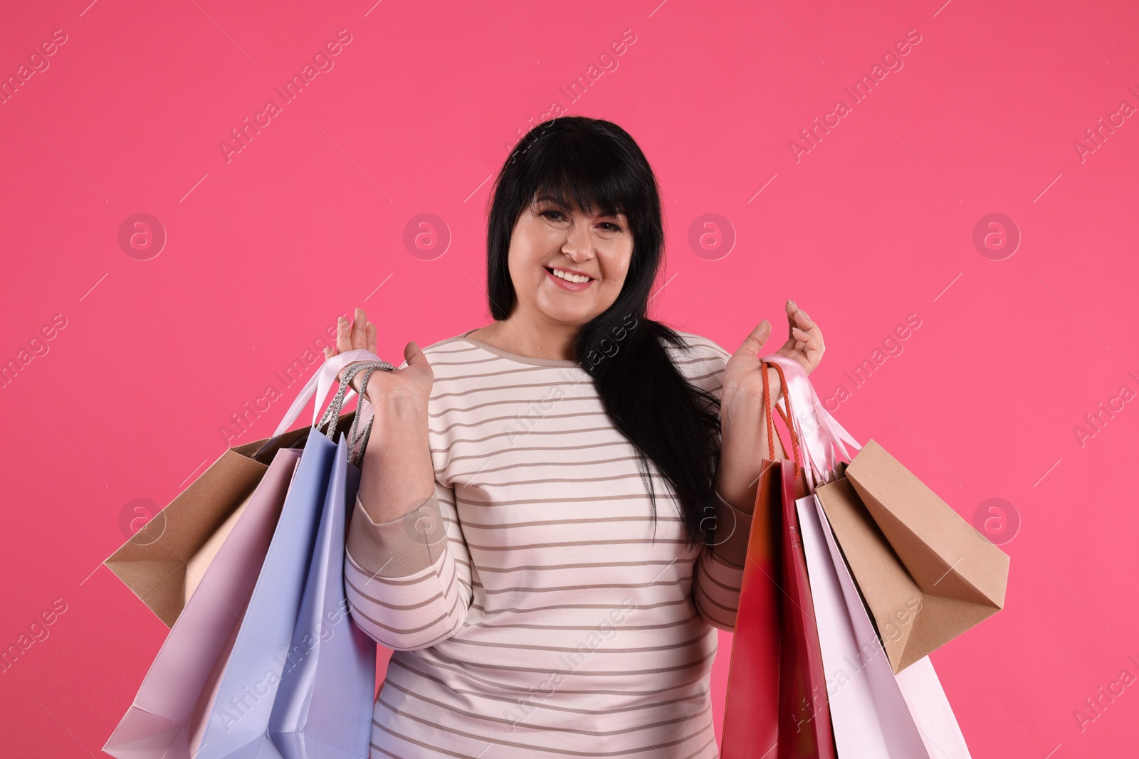 Photo of Beautiful overweight mature woman with shopping bags on pink background