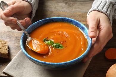 Woman eating sweet potato soup at table, closeup