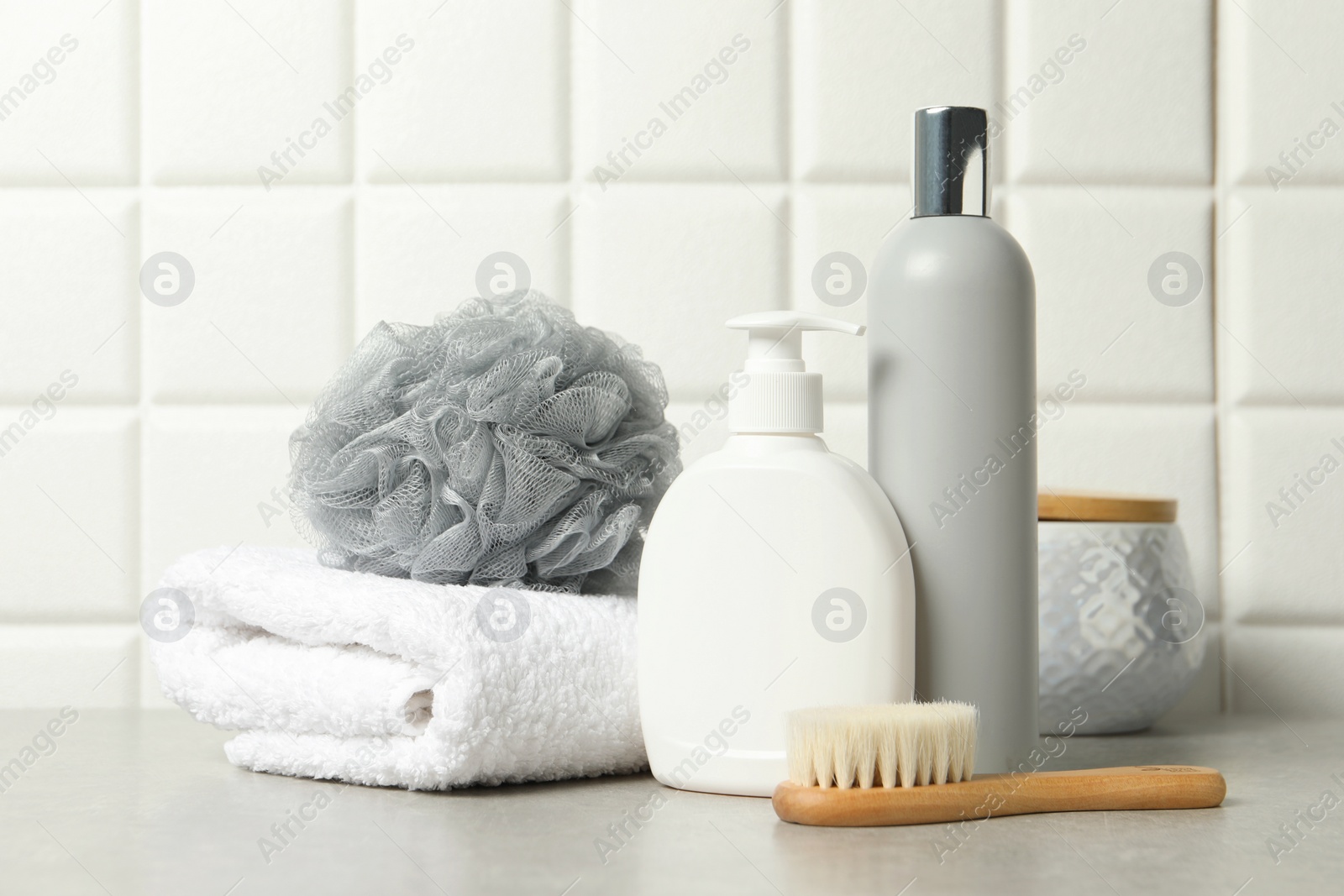 Photo of Different bath accessories and personal care products on gray table near white tiled wall