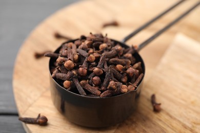 Aromatic cloves in scoop on table, closeup