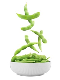 Green edamame pods falling into bowl on white background