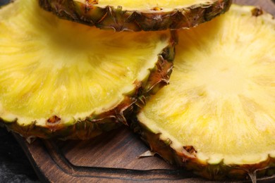 Photo of Slices of tasty ripe pineapple on wooden board, closeup