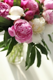 Photo of Vase with bouquet of beautiful peonies on table, above view