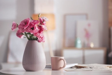 Photo of Vase with beautiful eustoma flowers on table in modern room interior, space for text