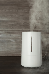 Photo of New modern air humidifier on wooden table