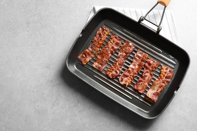 Grill pan with bacon on grey background