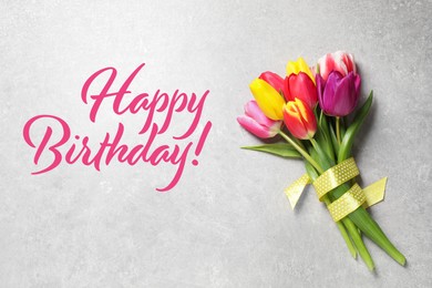 Image of Happy Birthday! Beautiful spring tulips on light grey stone table, top view 