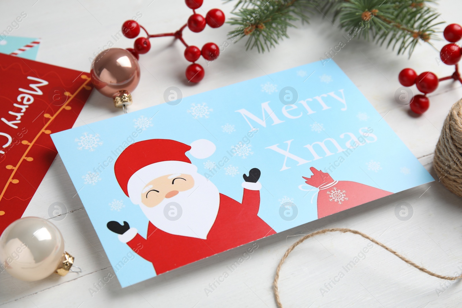 Photo of Christmas cards and festive decor on white wooden background