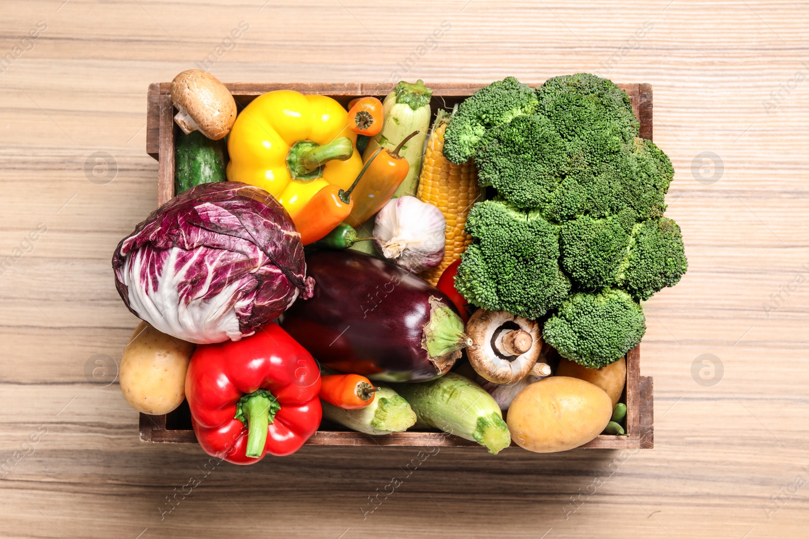 Photo of Crate with different fresh vegetables on wooden background, top view