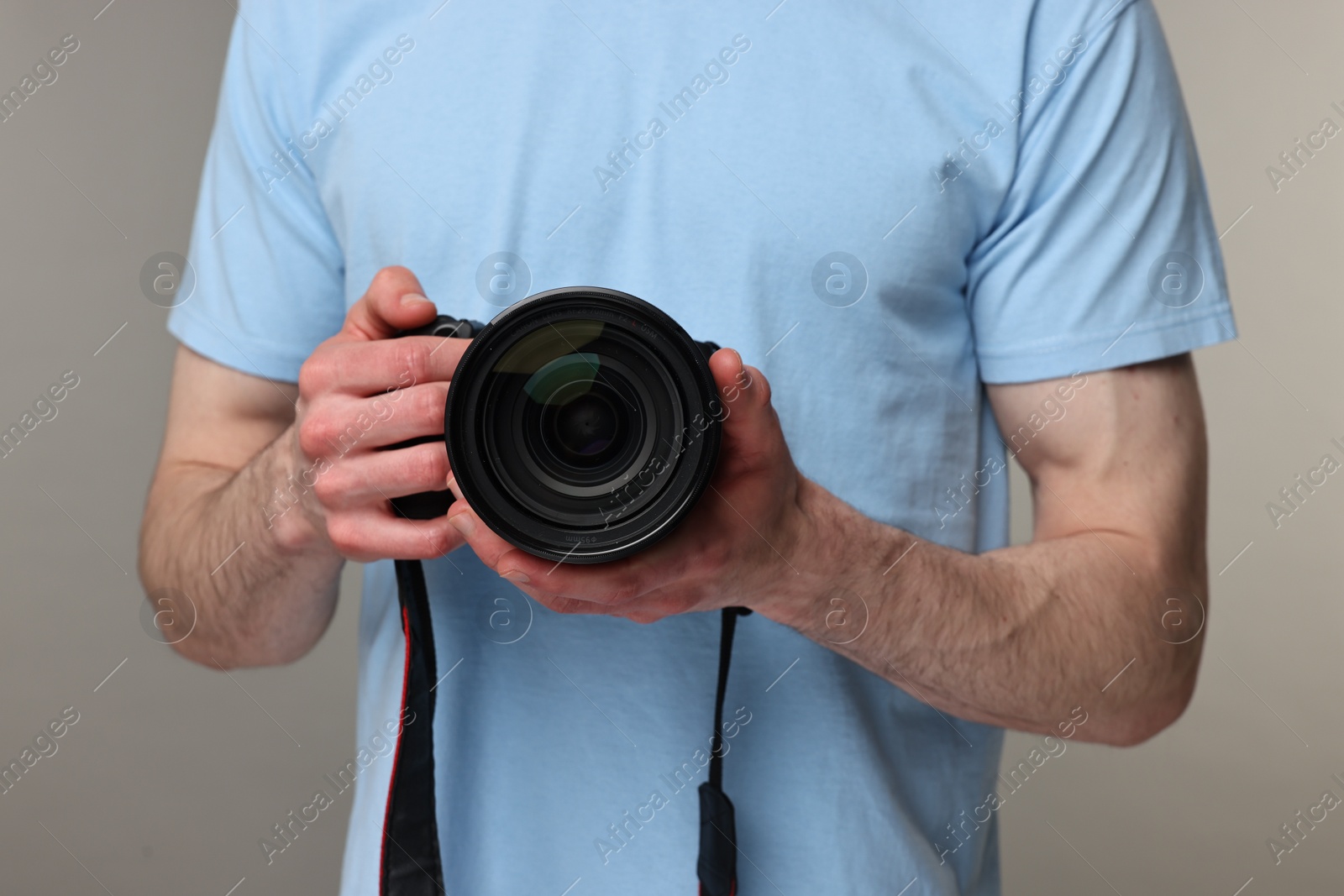 Photo of Photographer holding camera on grey background, closeup