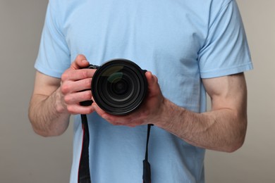 Photographer holding camera on grey background, closeup