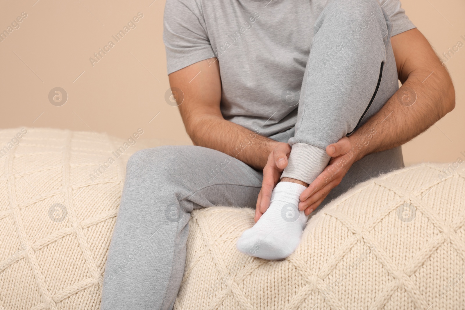 Photo of Man suffering from foot pain on bed indoors, closeup