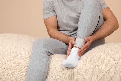 Man suffering from foot pain on bed indoors, closeup