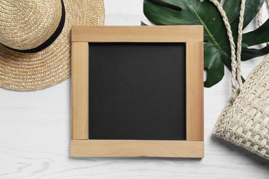 Photo of Blank chalkboard with stylish accessories and green leaf on white wooden table, flat lay. Space for text