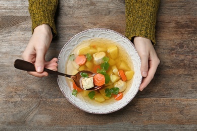 Photo of Woman eating fresh homemade chicken soup at table, top view