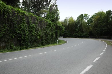 Photo of Picturesque view of asphalted roadway near beautiful trees and hedge