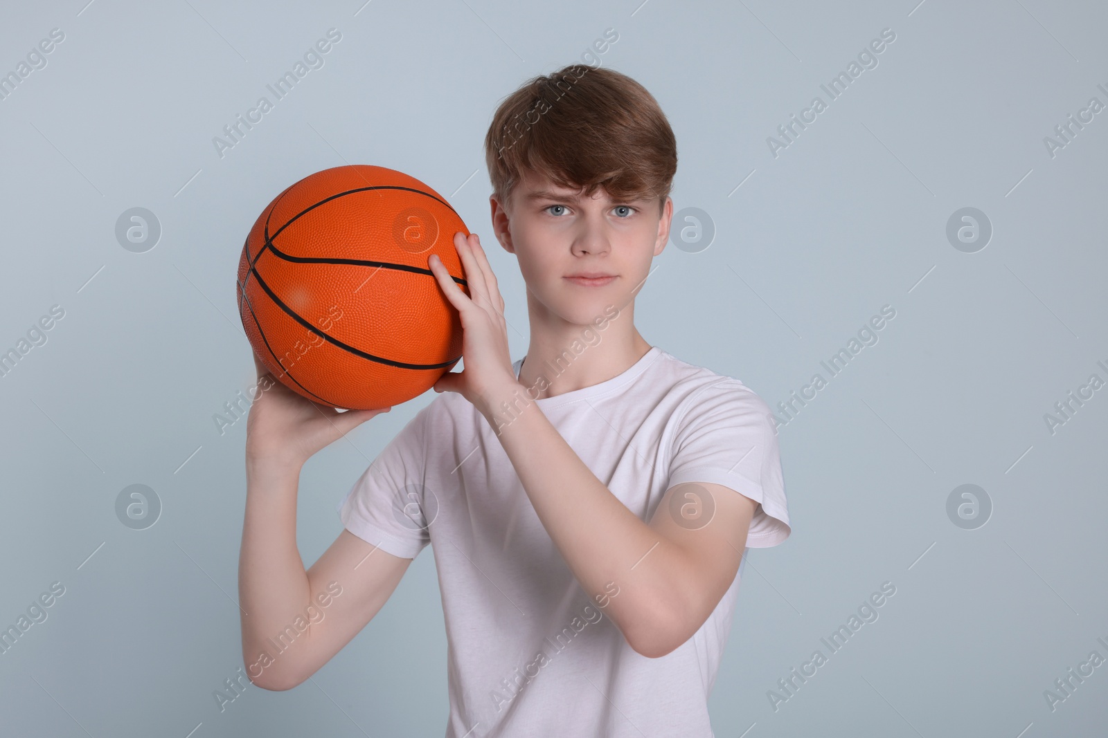 Photo of Teenage boy with basketball ball on light grey background