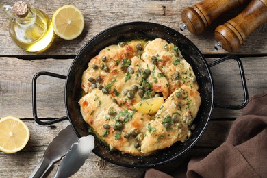 Photo of Delicious chicken piccata with herbs and lemon on wooden table, flat lay