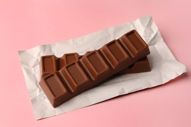 Photo of Paper wrap with delicious chocolate bars on pink background