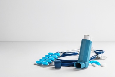 Photo of Asthma inhaler, stethoscope, pills and space for text on white background