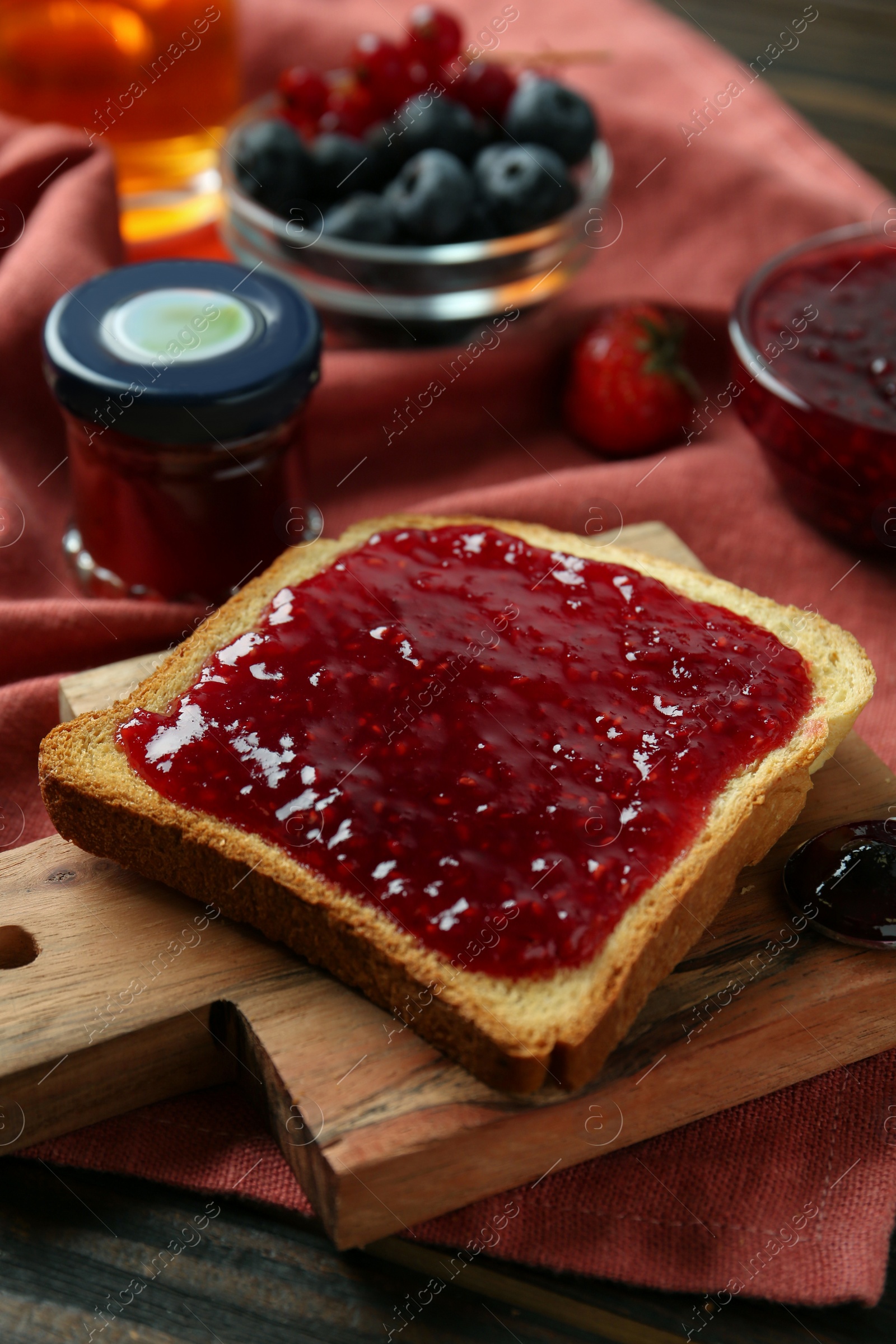 Photo of Delicious toast with jam on wooden board, closeup