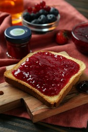 Photo of Delicious toast with jam on wooden board, closeup