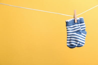 Photo of Small socks hanging on washing line against color background, space for text. Baby accessories