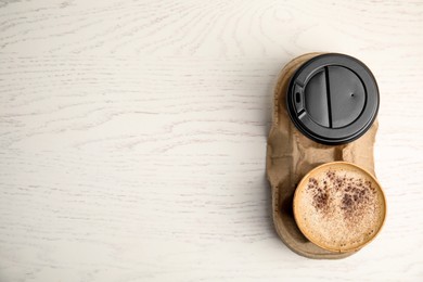 Takeaway paper cups with coffee in cardboard holder on white wooden table, top view. Space for text