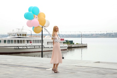 Photo of Beautiful young woman with bunch of balloons outdoors