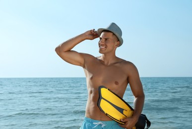 Happy man with flippers near sea on beach