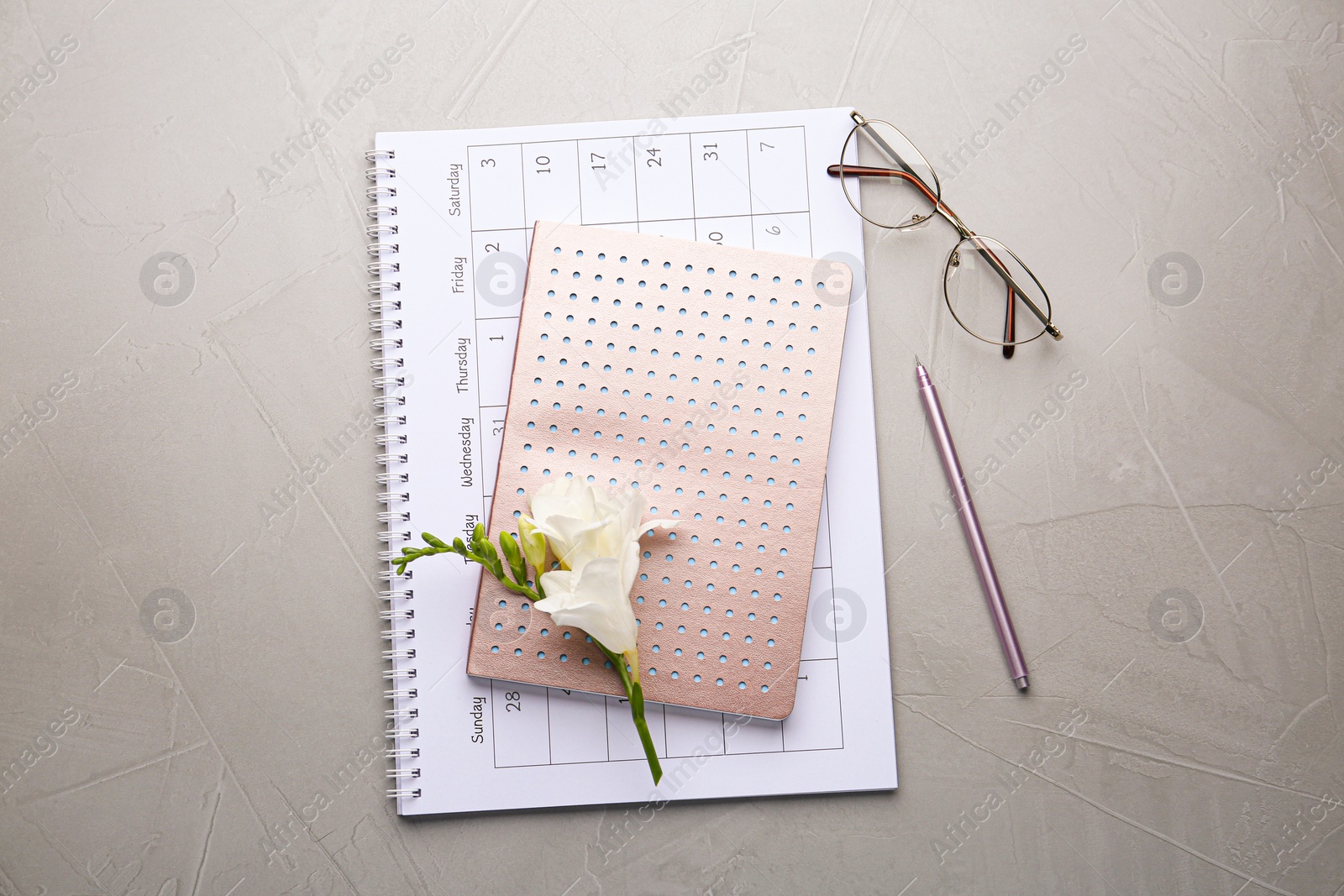 Photo of Flat lay composition with calendar, notebook and beautiful flower on grey table